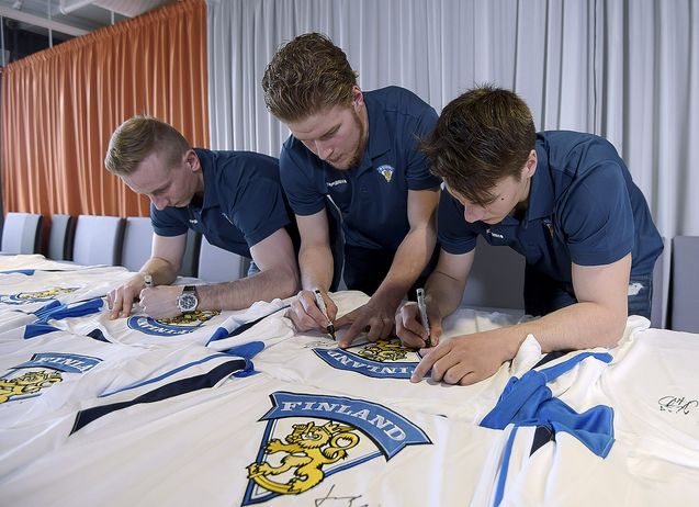 Juuso Hietanen (vas.) sekä maalivahdit Atte Engren (kesk.) ja Juuse Saros kirjoittavat nimikirjoituksia Leijonien maajoukkuepelipaitoihin A-maajoukkueen tiedotustilaisuudessa ennen Tshekkiin lähtöä. Kuva: Lehtikuva.