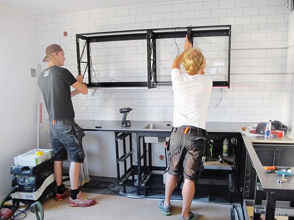 Ludde och kollegan Henrik monterar överskåp – avsevärt enklare med lätta Miinusstommen än vanliga spånskivekök. Den röda linjen på väggen är laservattenpasset.
