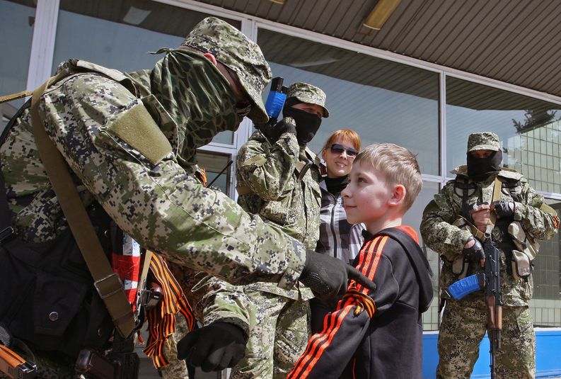 Venäläismielinen separatisti sitoo Yrjön nauhaa huhtikuussa 2014 Itä-Ukrainassa tms. Kuva: Igor Kovalenko.​