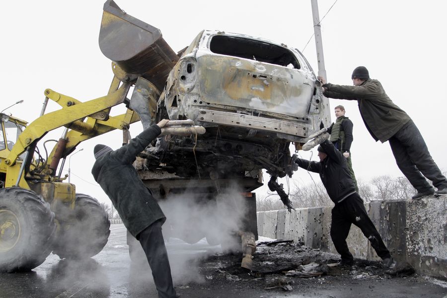 Taisteluissa tuhoutunutta autoa siirretään Donetskissa 10. helmikuuta. Kuva: Alexander Ermochenko/EPA