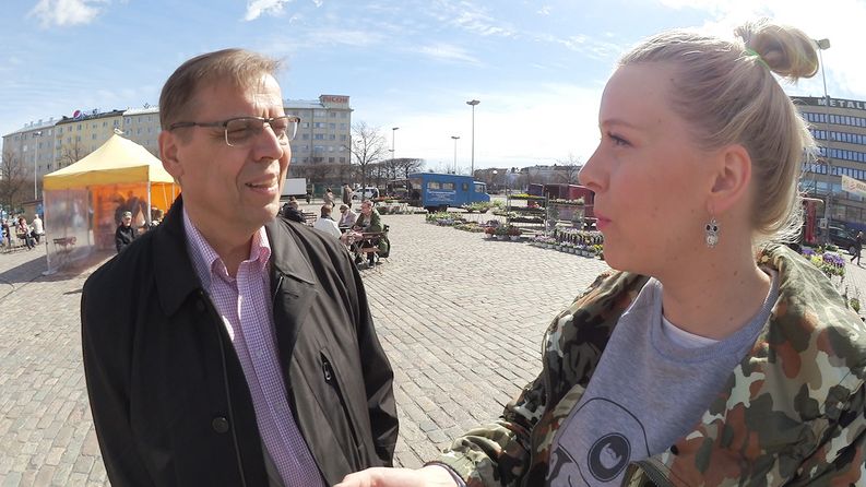 Lauri Lyly kertoo toimittaja Eve Väyryselle työväen vappuhuolista Hakaniemen torilla.​​