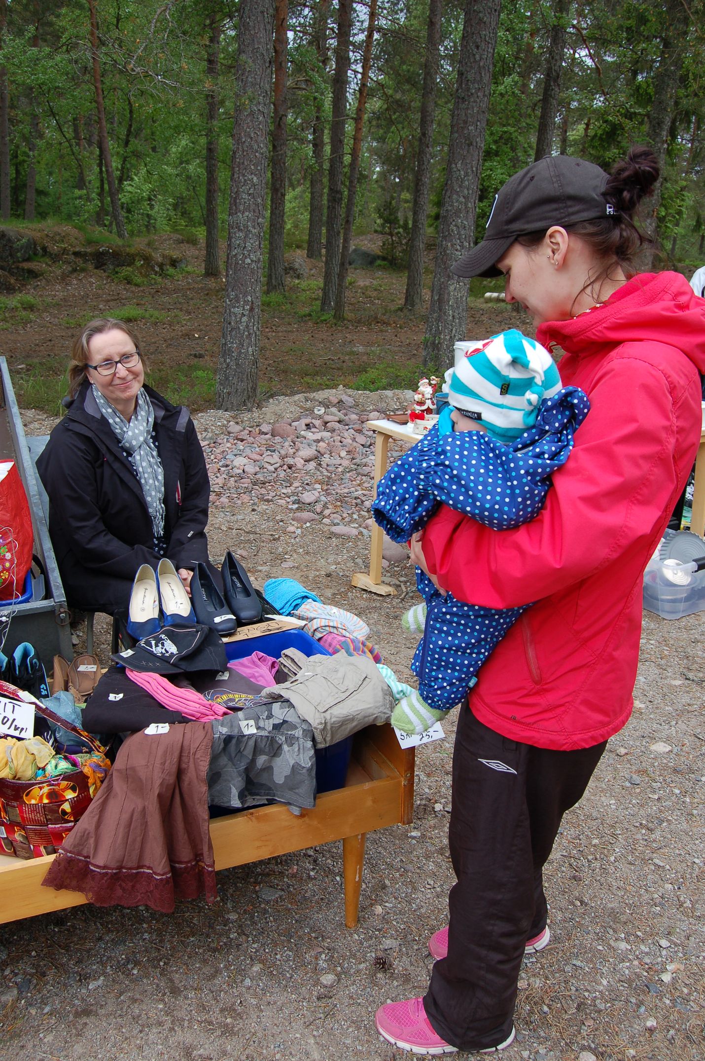 Sarianna ja Lukas Hannula tutkailevat Päivi Toivosen pöydän tarjontaa. Toivonen on tyytyväinen peräkärrykirppiksen järjestämisestä, sillä se mahdollistaa helposti isompien tavaroiden myynnin. Kuva: Elina Lammela