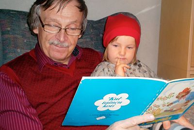 Pekka Pesonen läser med sitt barnbarn.​
