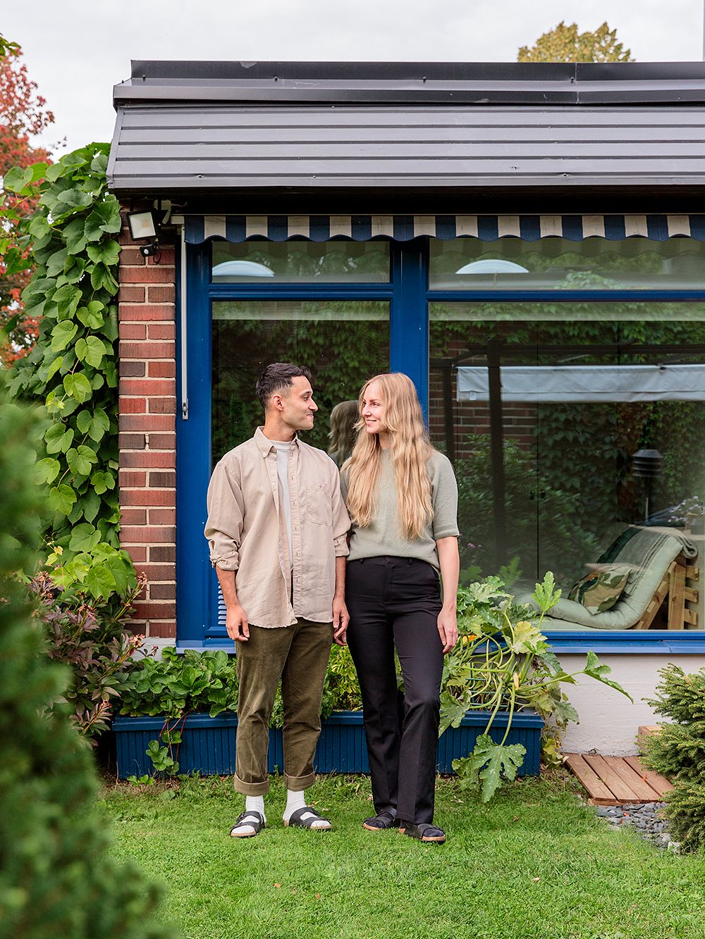 A couple standing outside a terraced house with a green yard