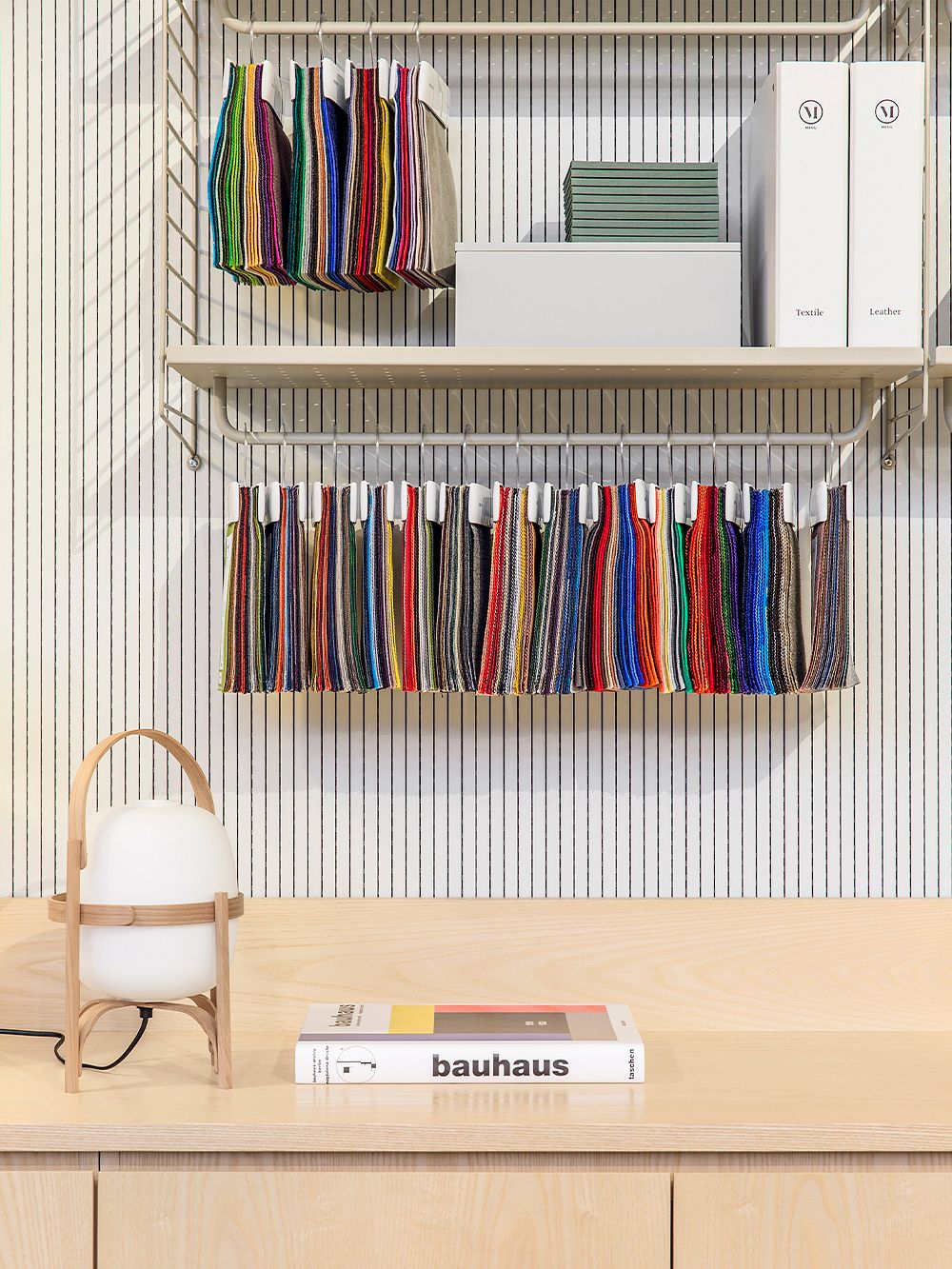Upholstery samples in different colors hang from a String shelf.