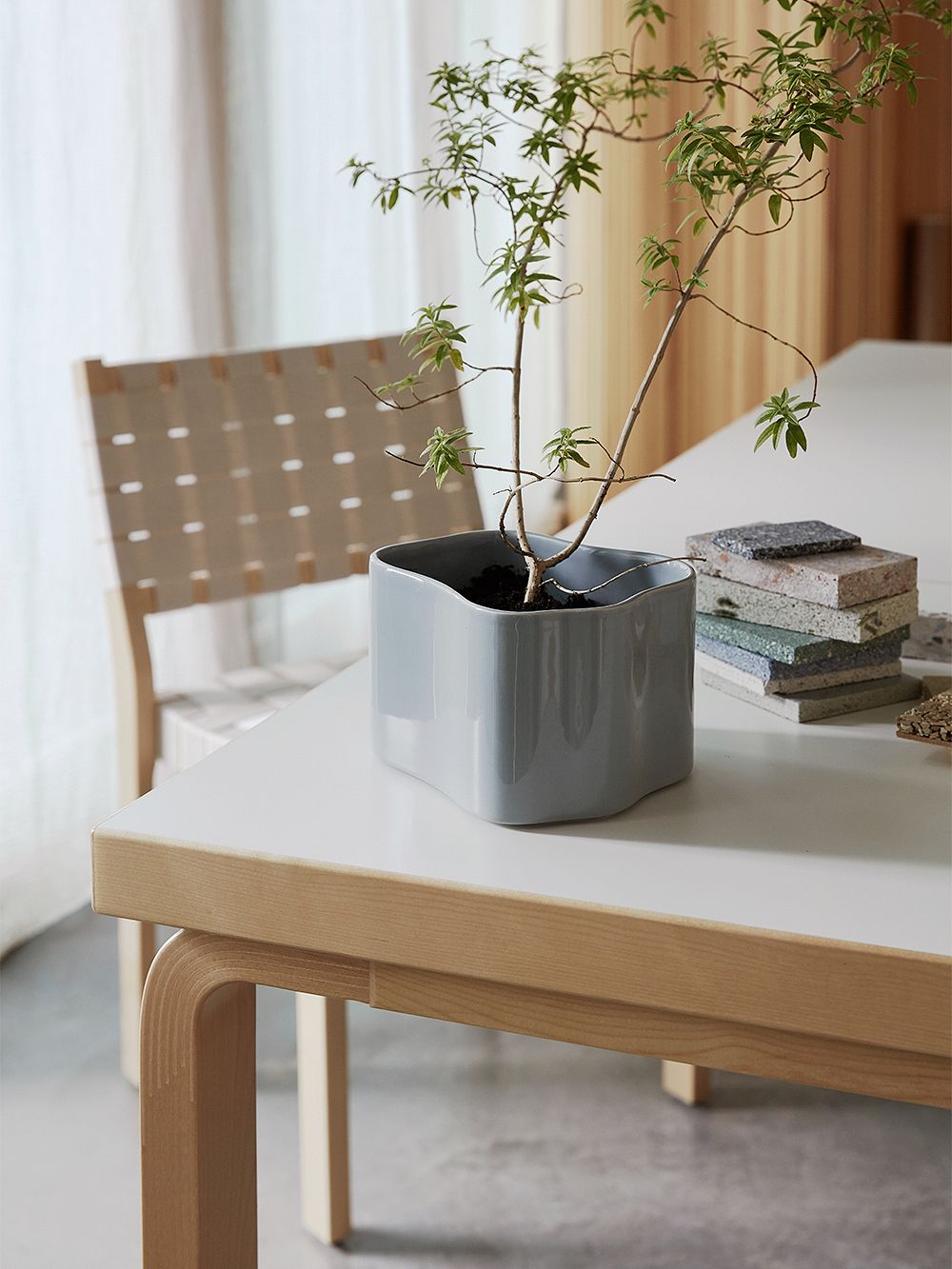 An image featuring Artek's grey Riihitie plant pot and Aalto chair 611 as part of the decor.