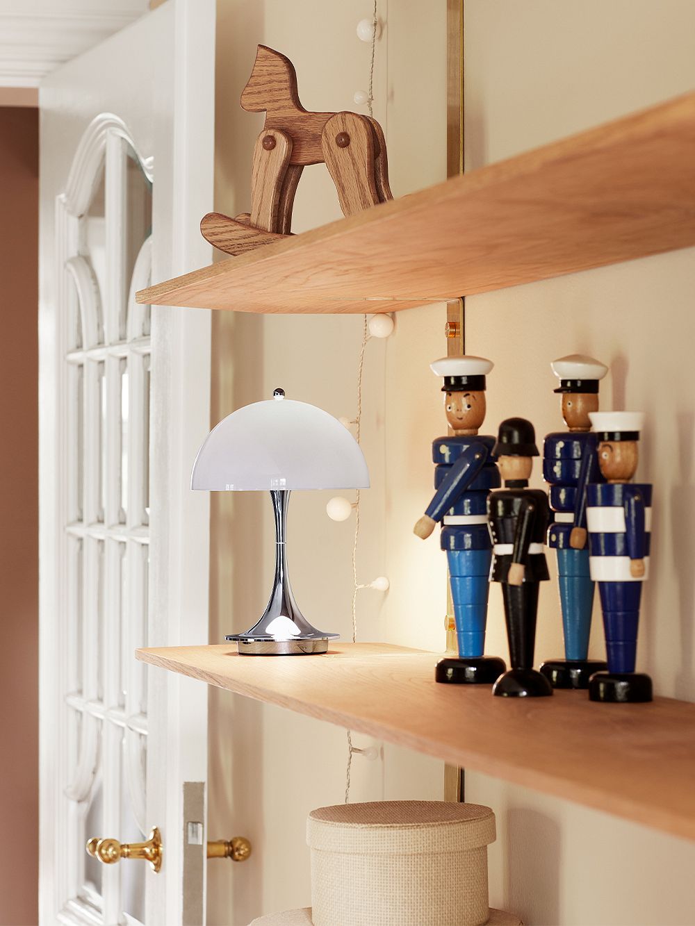 Louis Poulsen Panthella Mini lamp in grey and chrome on a shelf.