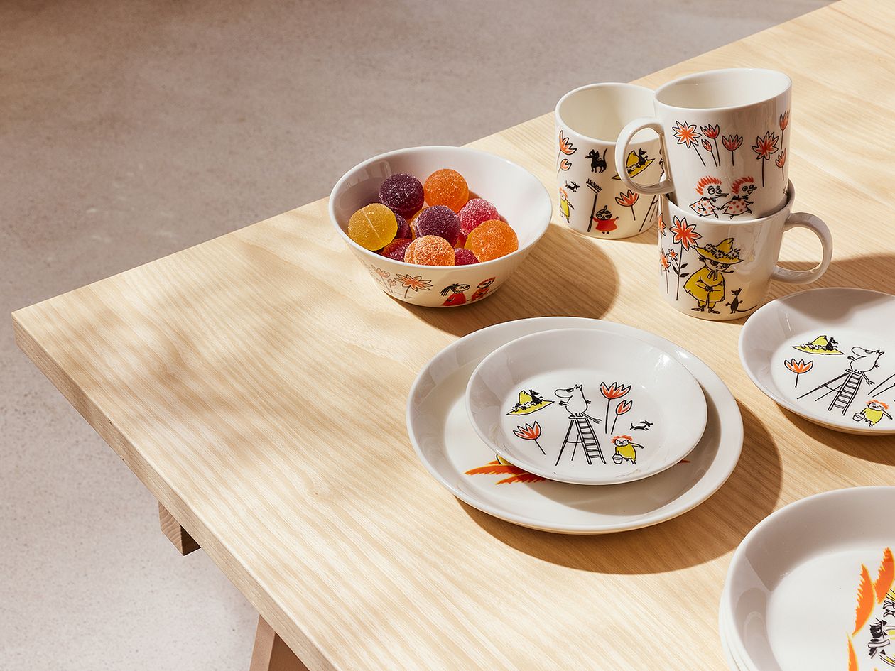 Moomin by Arabia x Red Cross Moomin ABC tableware piled on a wooden table