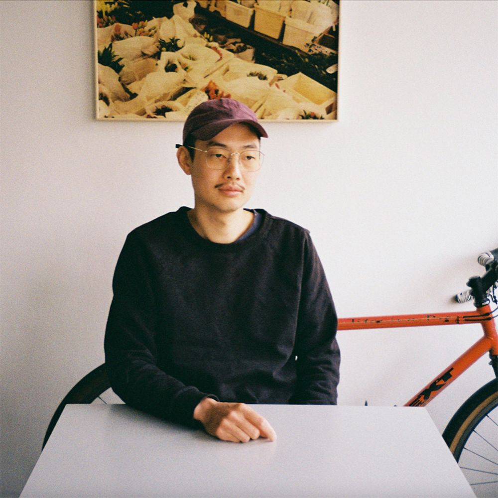 An image of designer Tom Chung sitting beside their work desk.