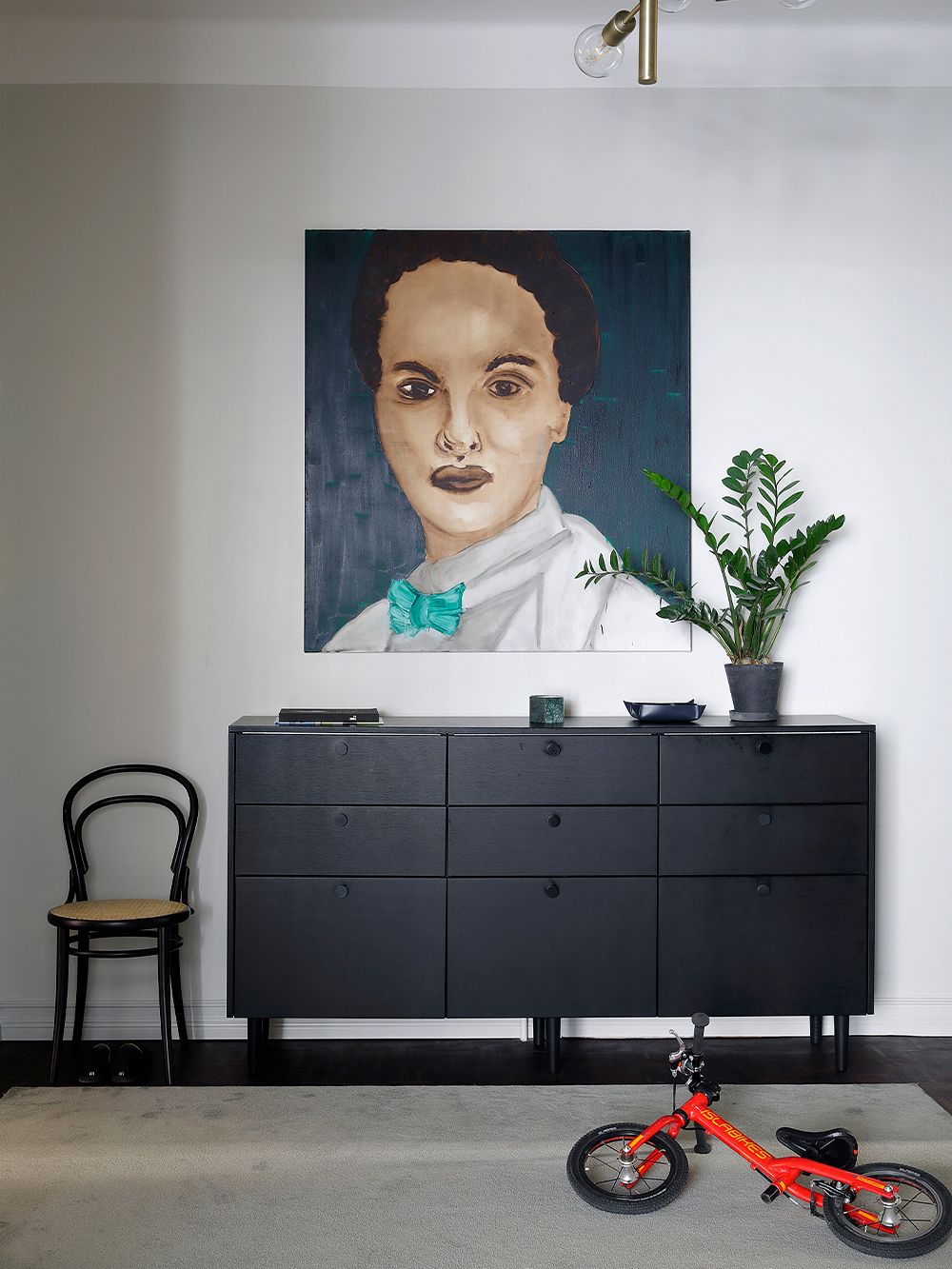 Black sideboard, red bicycle and a large portrait