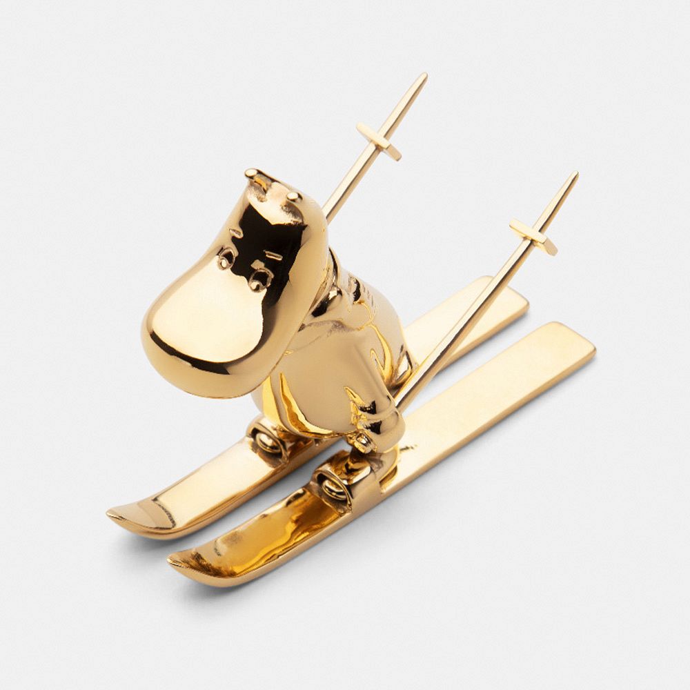 A gilded Moomintroll figurine with skis and sticks.