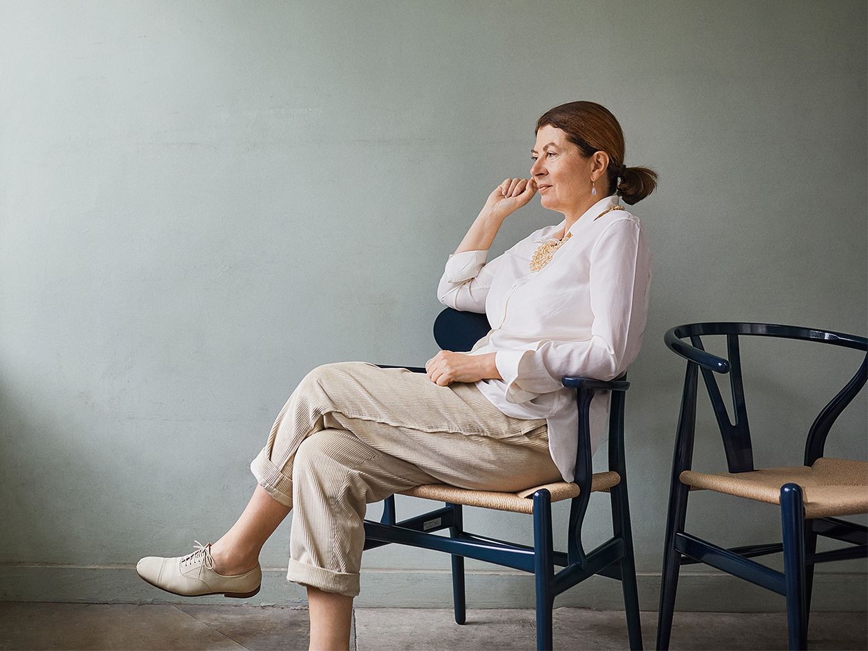 Designer Ilse Crawford sitting on a Wishbone chair.