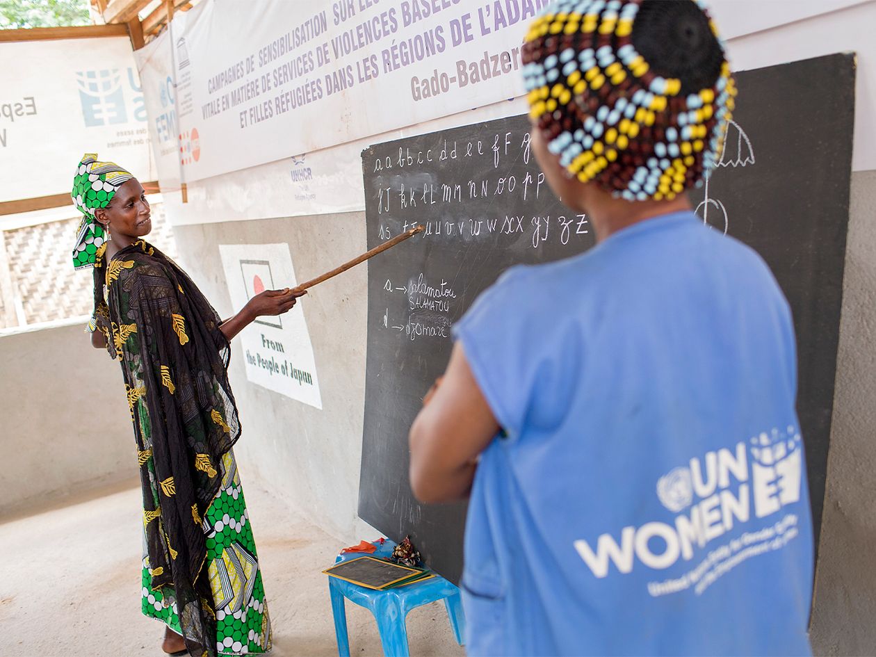 African woman pointing to the alphabet on a blackboard.