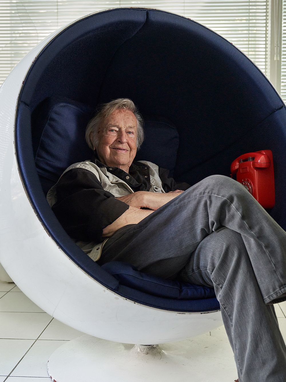 Eero Aarnio sitting in a white Ball Chair