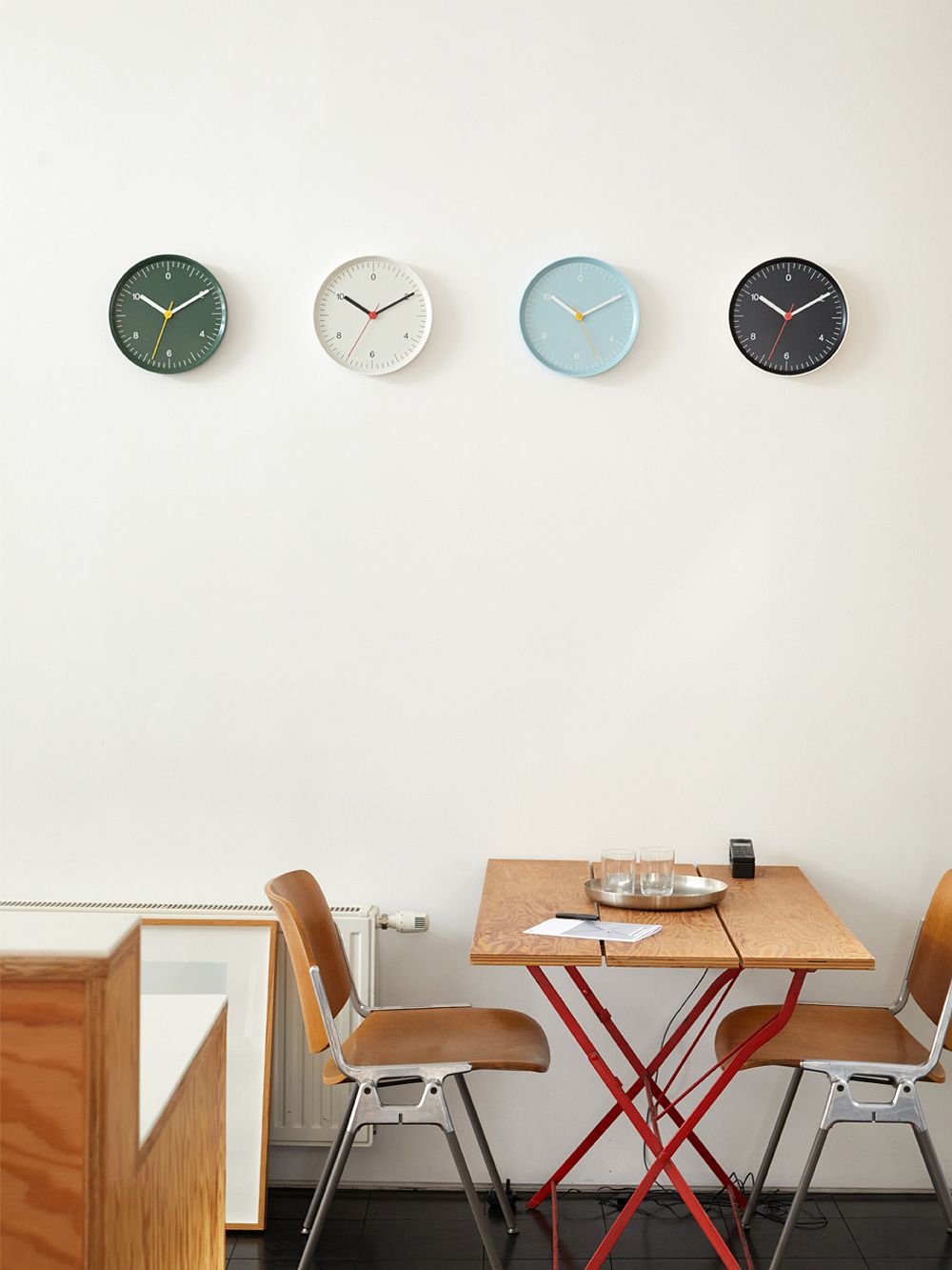 Four different coloured Wall Clocks hanging on the wall