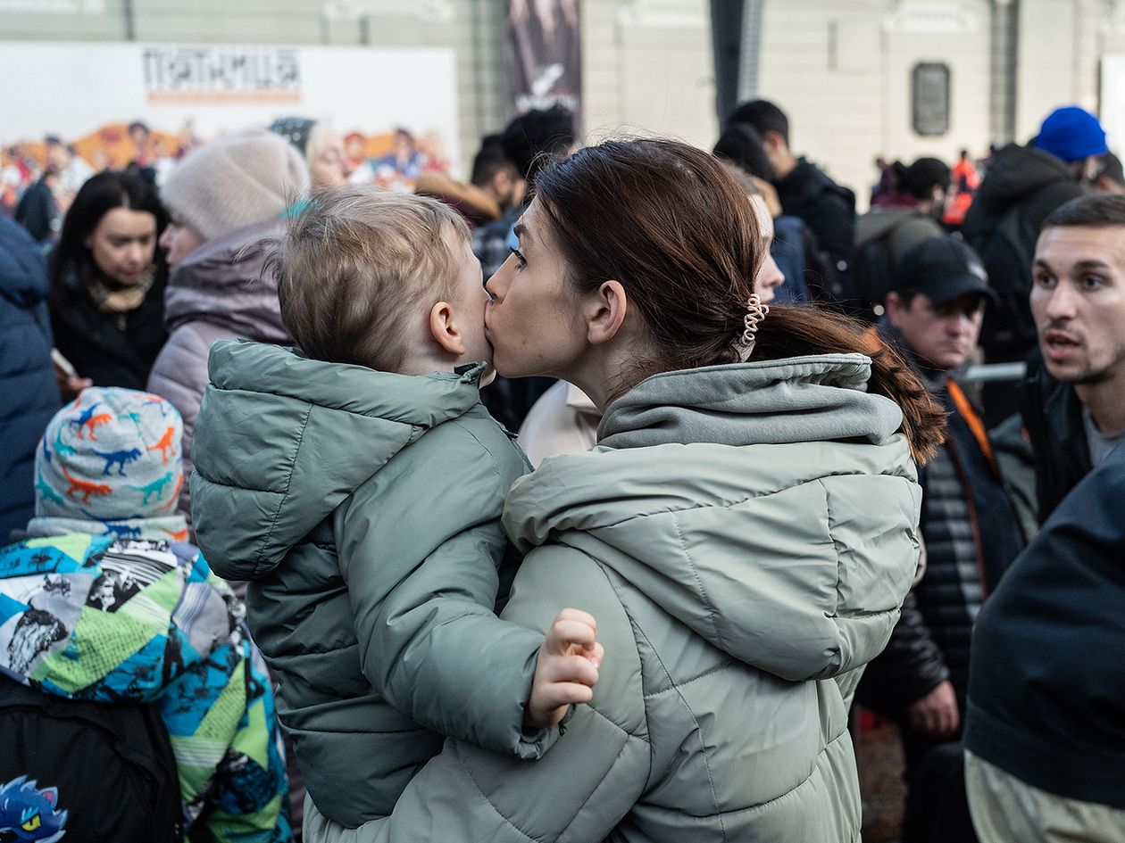 Ukrainian woman kisses the cheek of the child in her arms