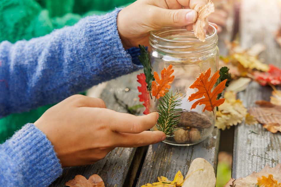 Zelfgemaakte kaarshouder met herfstbladeren en dennenappels.