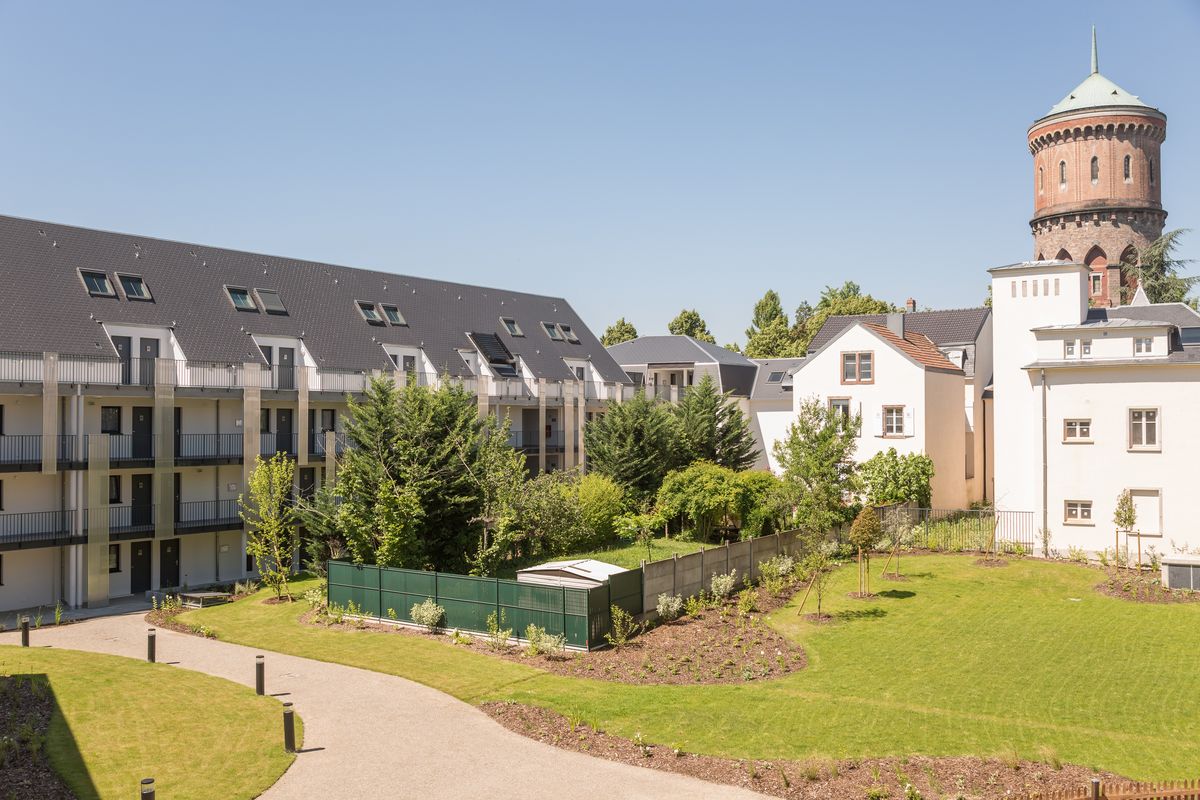 Vue sur la résidence Pierre & Vacances La Petite Venise à Colmar, avec ses bâtiments modernes et son jardin arboré sous un ciel ensoleillé.