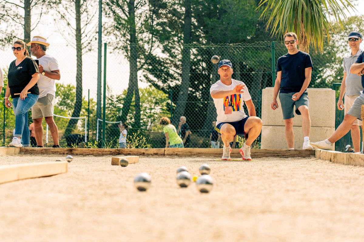 Vacanciers jouant à la pétanque en plein air, activité conviviale et intergénérationnelle pendant un séjour Pierre & Vacances.