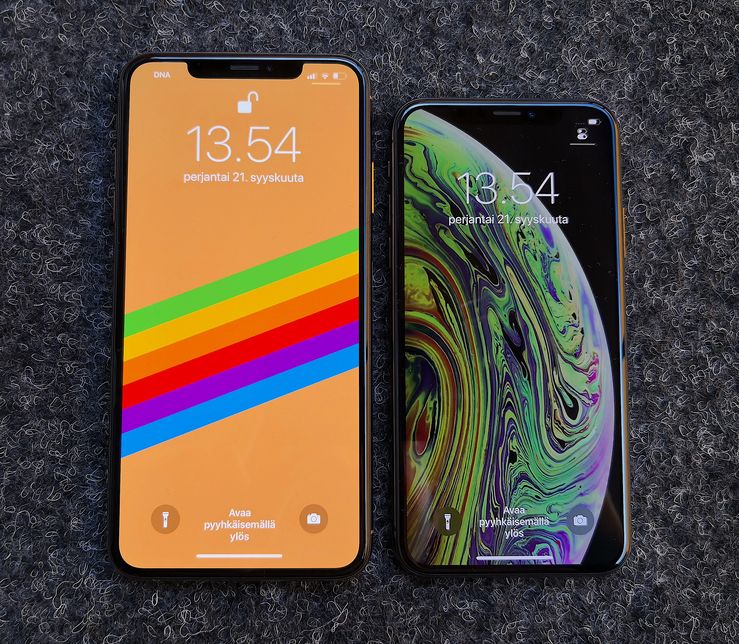 iPhone XS Max ja iPhone XS ovat varustettu laadukkailla OLED-näytöillä. Oikealla olevan iPhone XS:n näytöllä näkyvä oletustaustakuva jättää loven piiloon ollessaan musta yläreunasta.