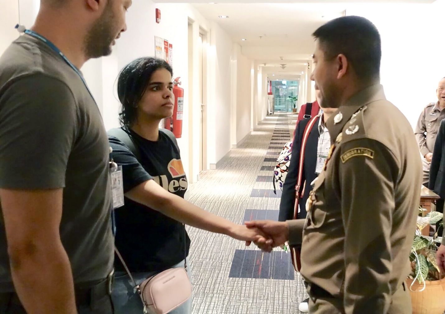 Rahaf Mohammed al-Qunun (vas.) tervehti Thaimaan maahanmuuttopoliisin päällikköä Surachet Hakparnia maanantaina Bangkokin lentoasemalla.