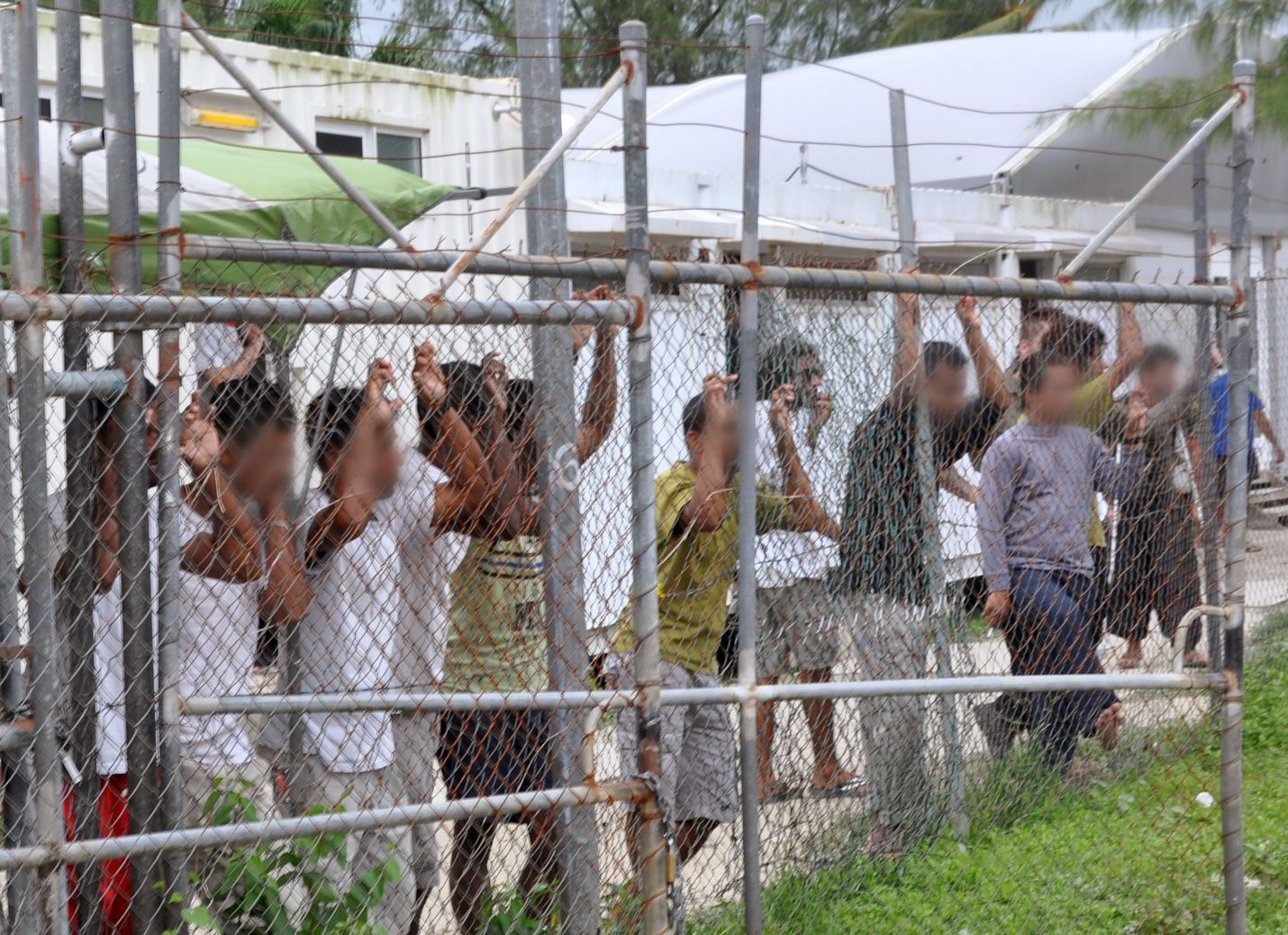 Turvapaikanhakijat katselivat tiedotusvälineiden edustajia Australian vastaanottokeskuksen aidan takaa Manusin saarella Papua-Uudessa-Guineassa vuonna 2014.