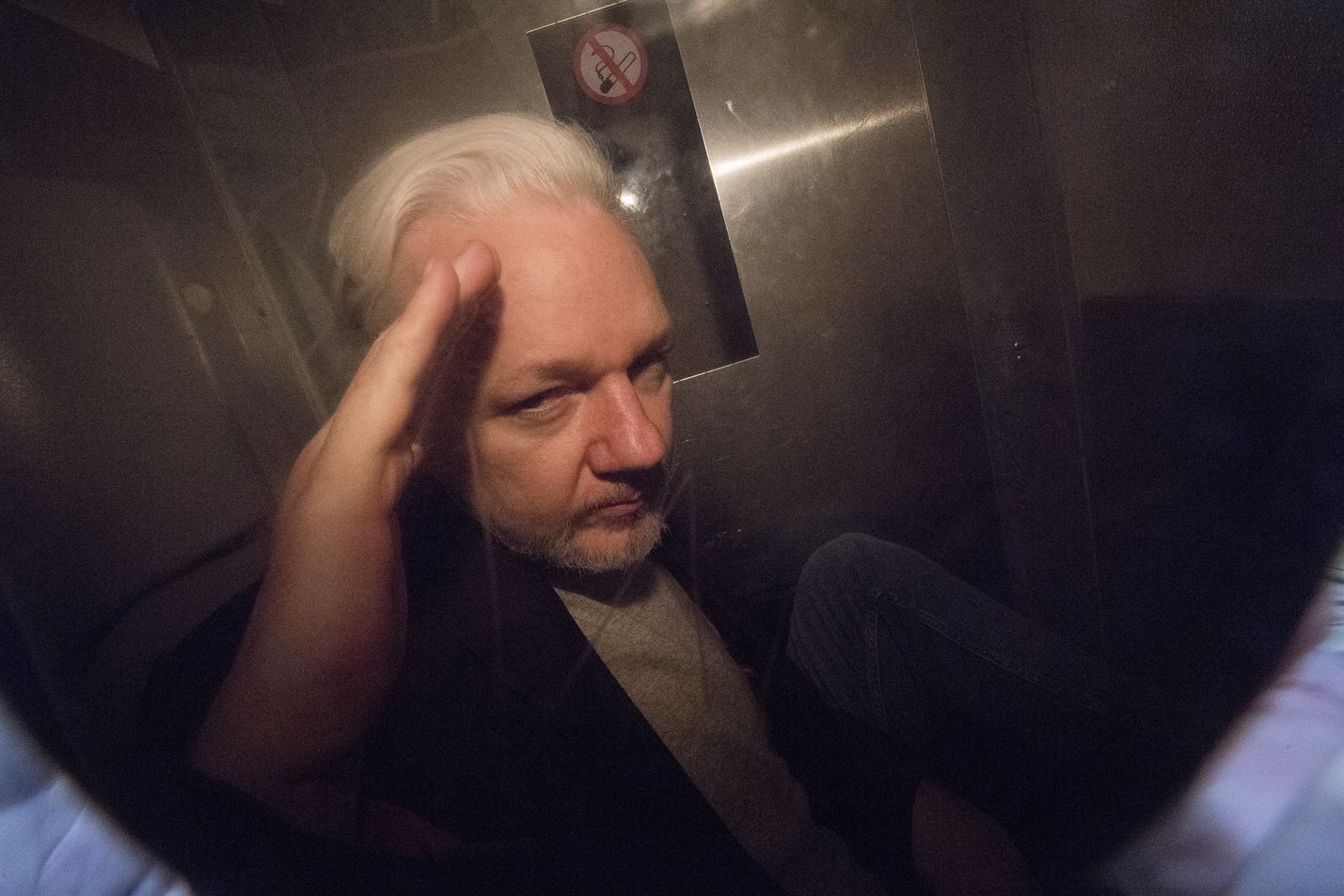 Julian Assange elehti poliisiauton lasin takaa valokuvaajille huhtikuussa Lontoossa.