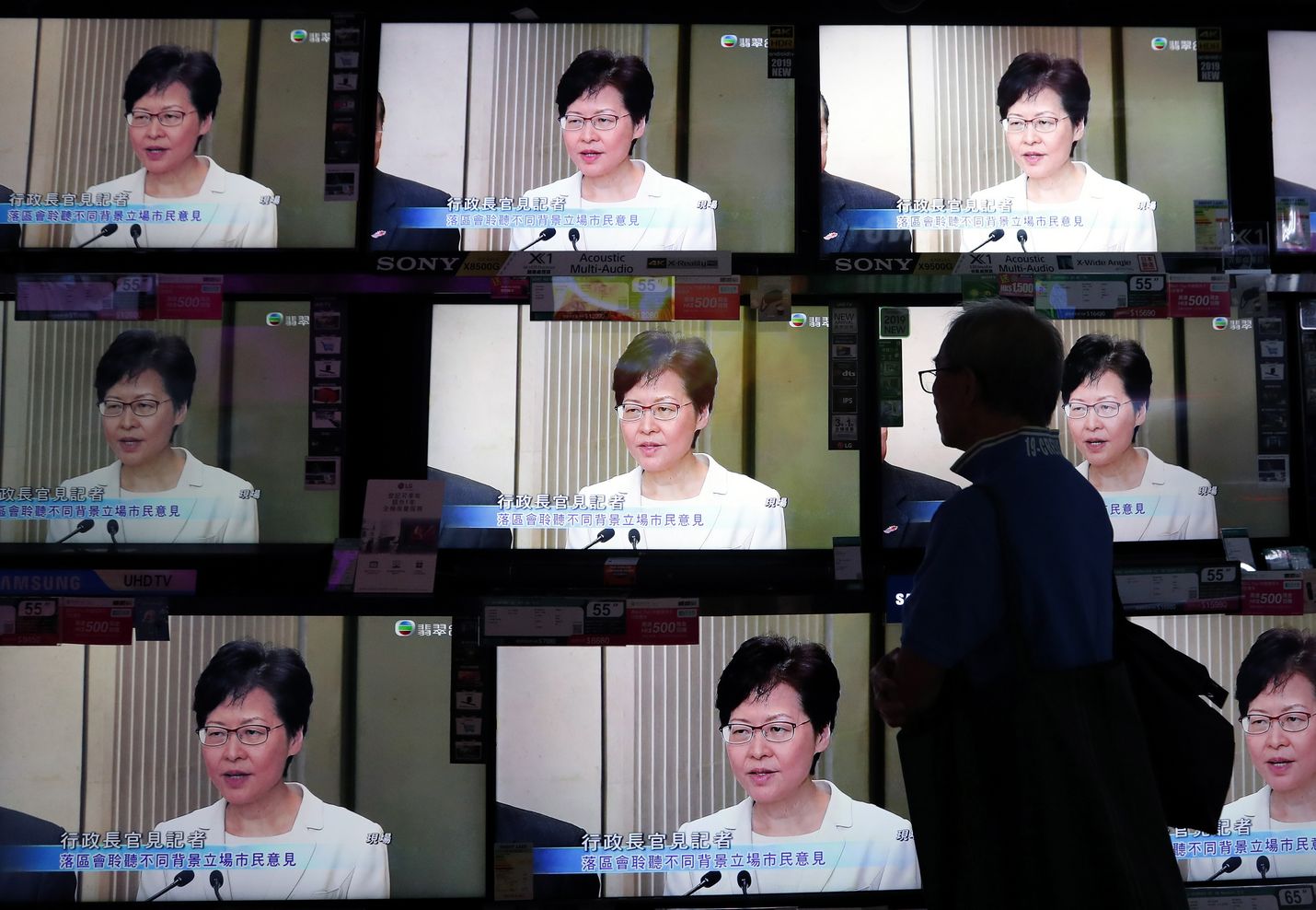 Hongkongilainen mies katseli kadulla televisiosta, kun hallintojohtaja Carrie Lam piti tiedotustilaisuutta torstaina kiistellyn luovutuslain kohtalosta.