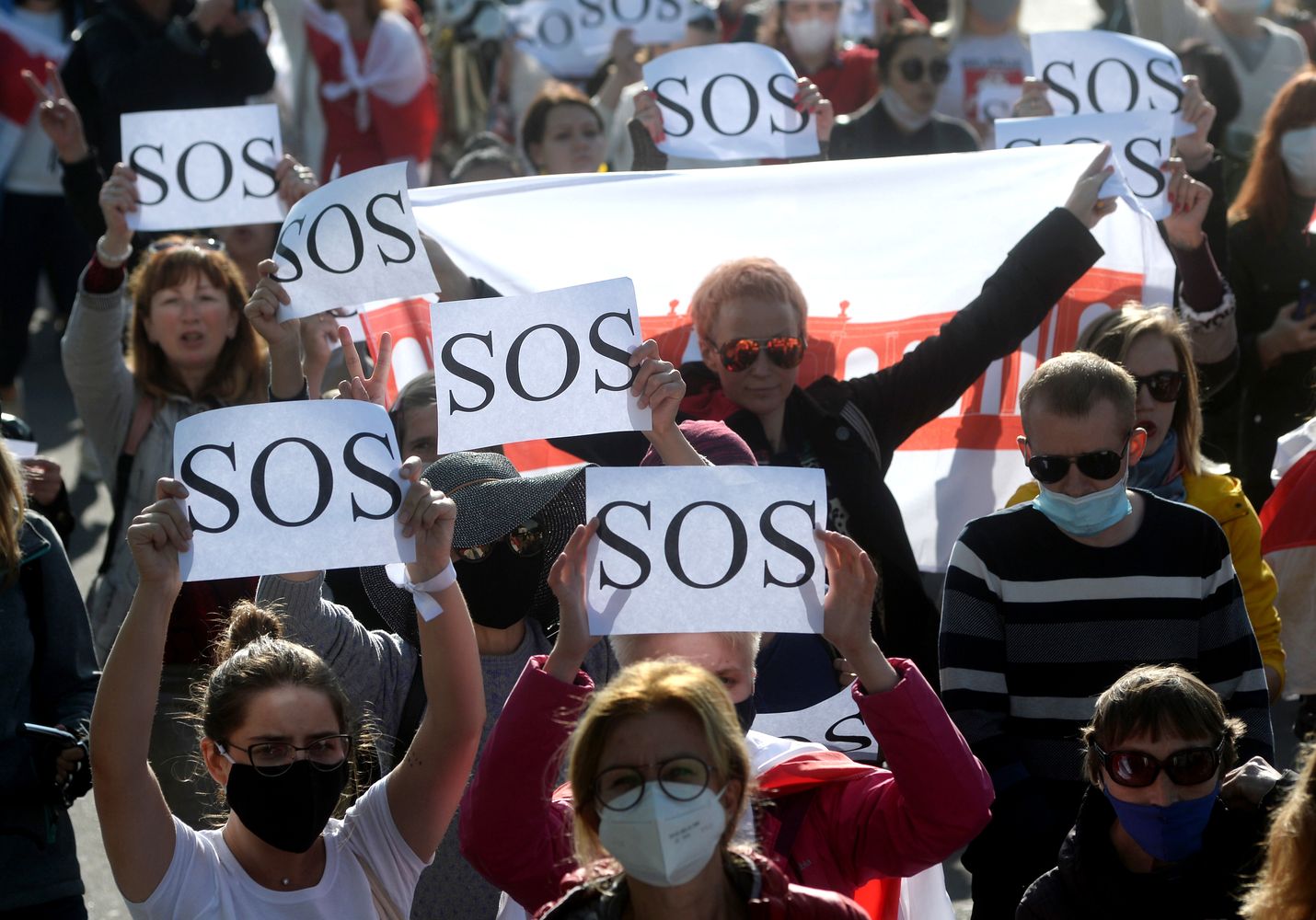 Naiset kantoivat SOS-kylttejä lauantaina Minskissä järjestetyssä protestissa. Satoja osallistujia pidätettiin.