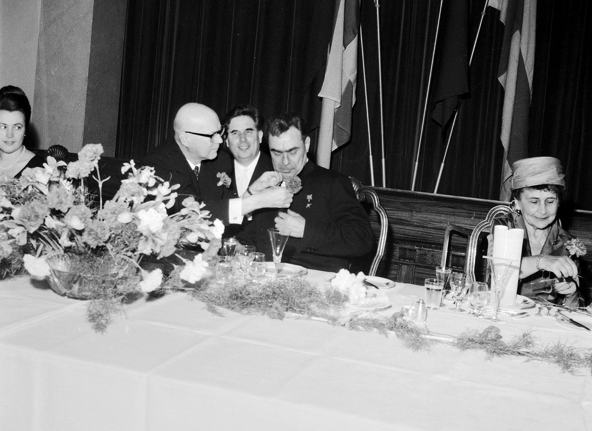 Presidentti Urho Kekkonen kiinnittää neilikkaa Neuvostoliiton presidentin Leonid Brežnevin rintaan juhlalounaalla syksyllä 1961. Oikealla Sylvi Kekkonen. Kuva: Kauko Kanerva / Museovirasto.