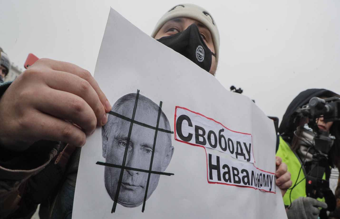 Protestoija pitelee lappua, jossa vaaditaan vapautta Navalnyille. Kaltereiden taakse toivotetaan puolestaan Putinia.
