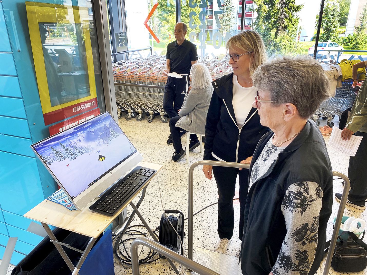 Irma Koskela kävi maanantaina K-Supermarket Rosmariinin aulassa kokeilemassa tasapainolaitteella, kuinka tasapainoilu pelissä sujuu. Auli Kouru Rauman kaupungin liikuntatoimesta ohjeistaa vierestä. 