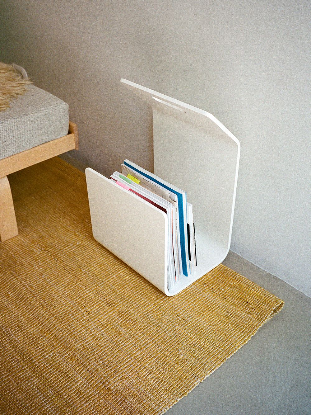 An image of Artek's white Kanto magazine or firewood rack as part of the living room decor.