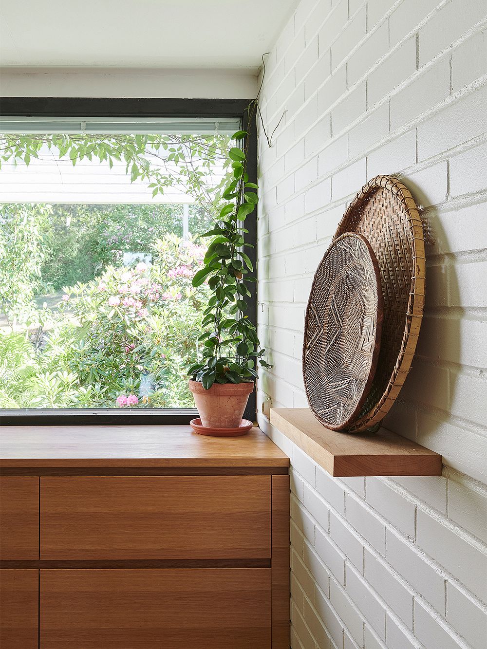 Kuva keittiöstä, jossa on tammiovinen kaapisto ikkunan alla