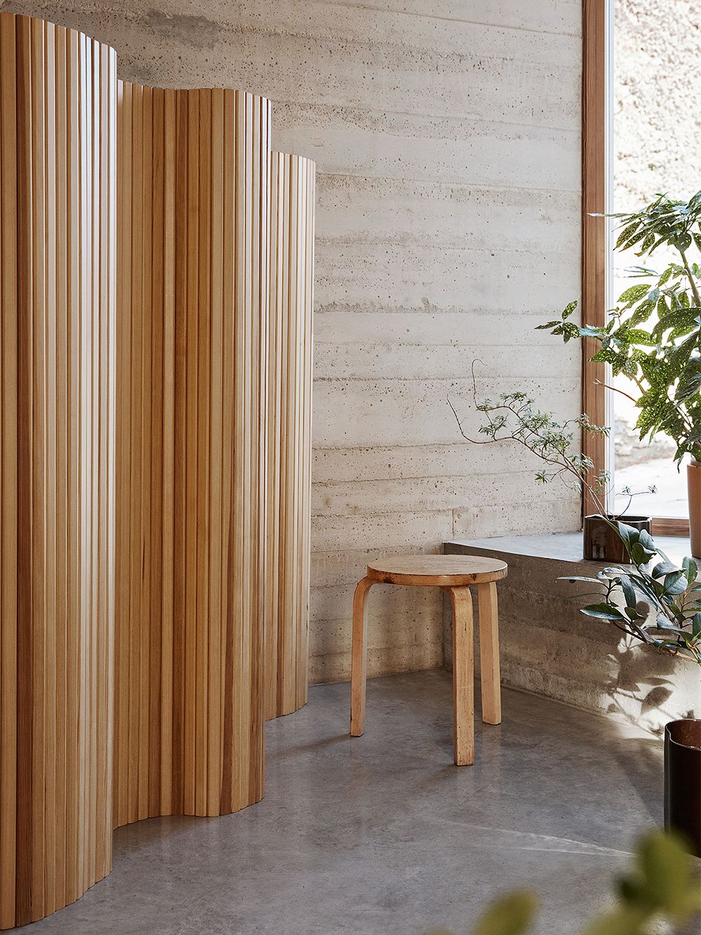 An image of Artek's Aalto stool 60 in a birch hue and Artek's Aalto screen 100 as part of the living room decor.