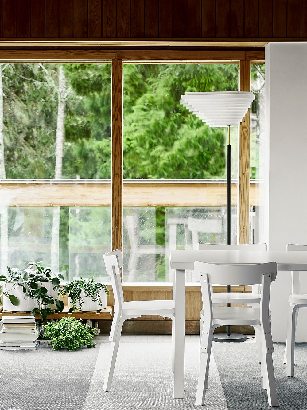 Kuva, jossa Artekin valkoisia Aalto-tuoleja Aalto-pöydän ympärillä, osana ruokailutilan sisustusta. Kuvassa myös A805-lattiavalaisin.