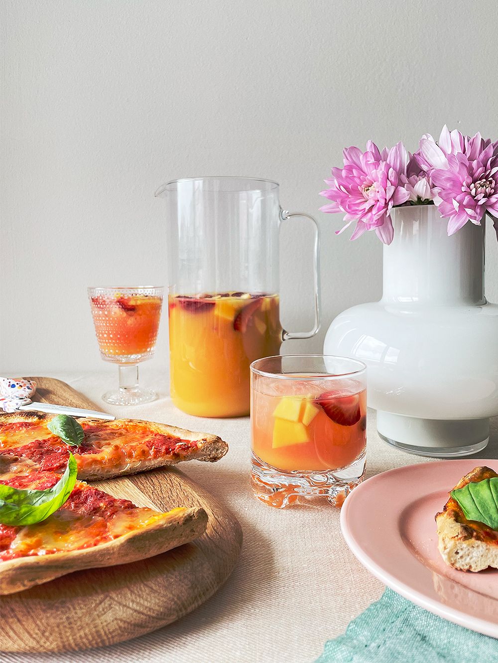 An image of Iittala's Kastehelmi glass, Woody chopping board and HAY's Rainbow plate in a table setting.