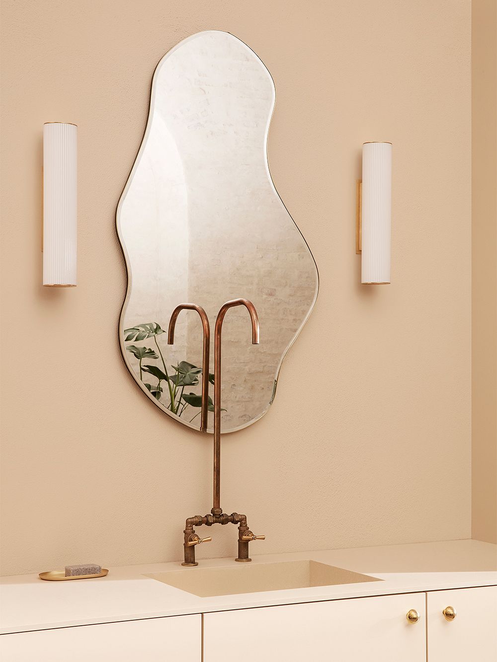 An image of ferm LIVING's Vuelta wall lamps and Pond mirror as part of the bathroom decor.