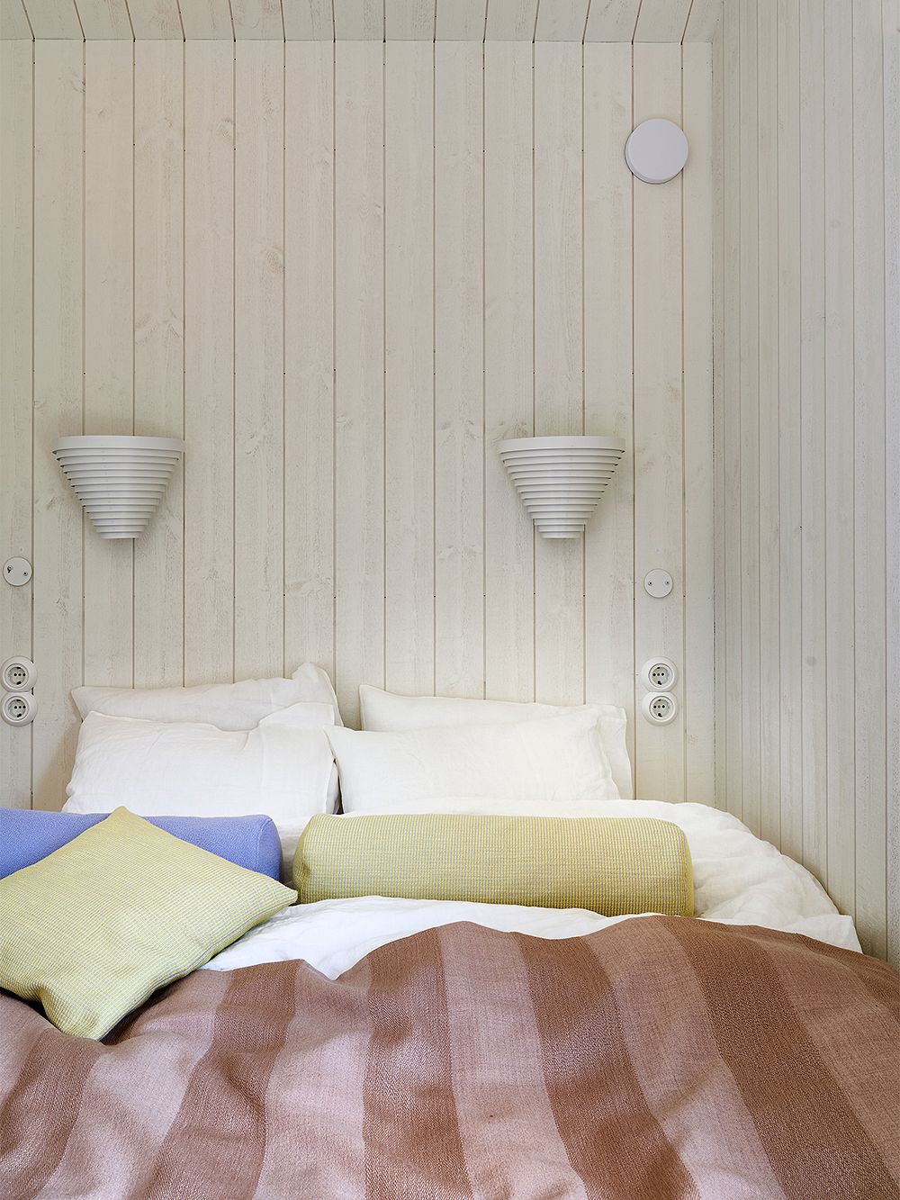 Kuva, jossa Fiskars Biennalen Arkkitehdin talo -näyttelyssä mukana oleva Sommarnöjenin Sommar 30 -mökki: Artekin 910-seinävalaisimet osana makuuhuoneen sisustusta.