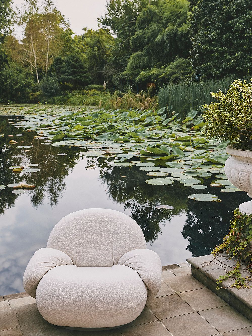 An image of GUBI's Pacha Outdoor armchair in a garden.