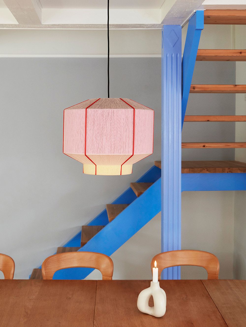 Ruokapöydän yllä HAYn vaaleanpunainen Bonbon-varjostin ja taustalla siniseksi maalattu portaikko