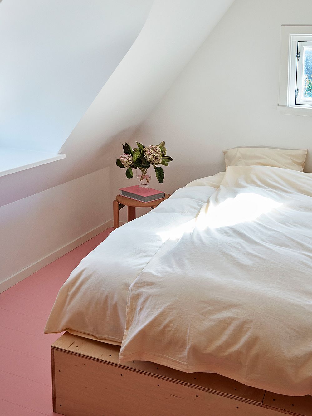 Makuuhuoneessa vaaleanpunainen lattia ja sänkyyn pedattu HAYn luonnonvalkoiset Duo-pussilakanat.