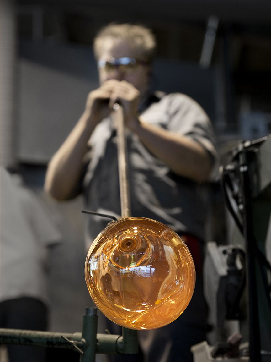 Lasinpuhaltaja puhaltamassa ilmaa lasikuplaan Iittalan lasitehtaalla