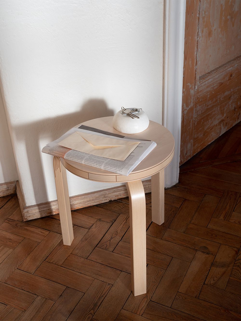 Artek Aalto jakkara 60 Kontrastin päällä postia ja pieni kulho avaimille