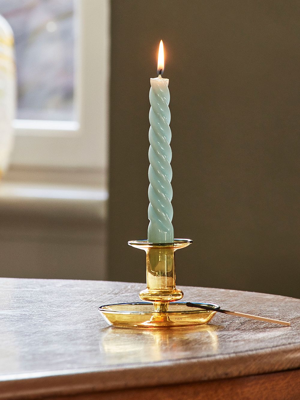 Kuva, jossa HAYn Twist-kierrekynttilä Flare-kynttilänjalassa osana kodin joulusisustusta.
