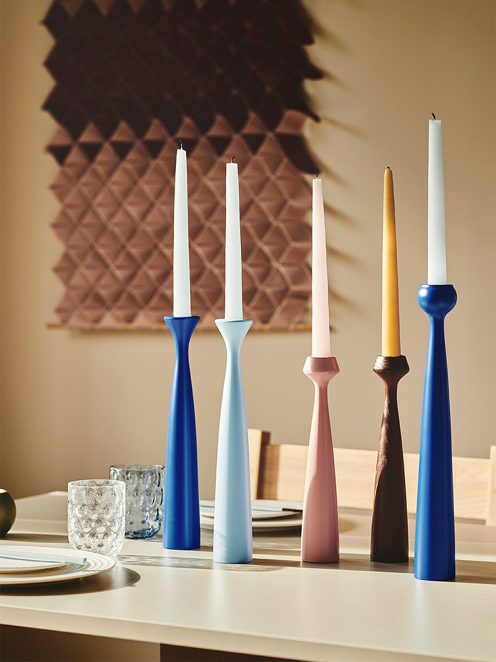 An image featuring applicant's wooden Blossom candleholders and candles in many bright hues, placed on the table, as part of the dining room decor.