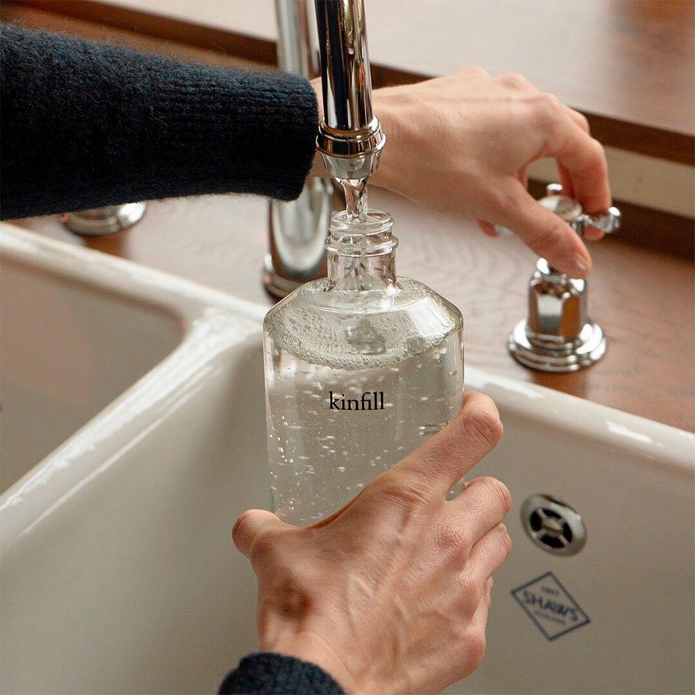 Kuva, jossa Kinfillin lasiseen pulloon lasketaan vettä hanasta.