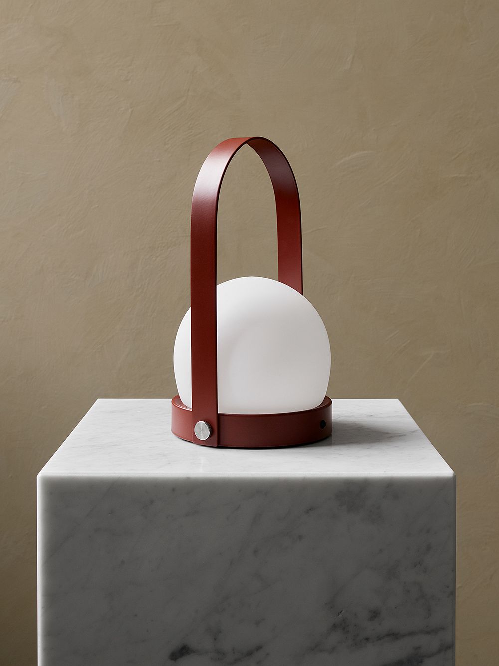 An image of Menu's Carrie LED table lamp in red set on a marble side table.
