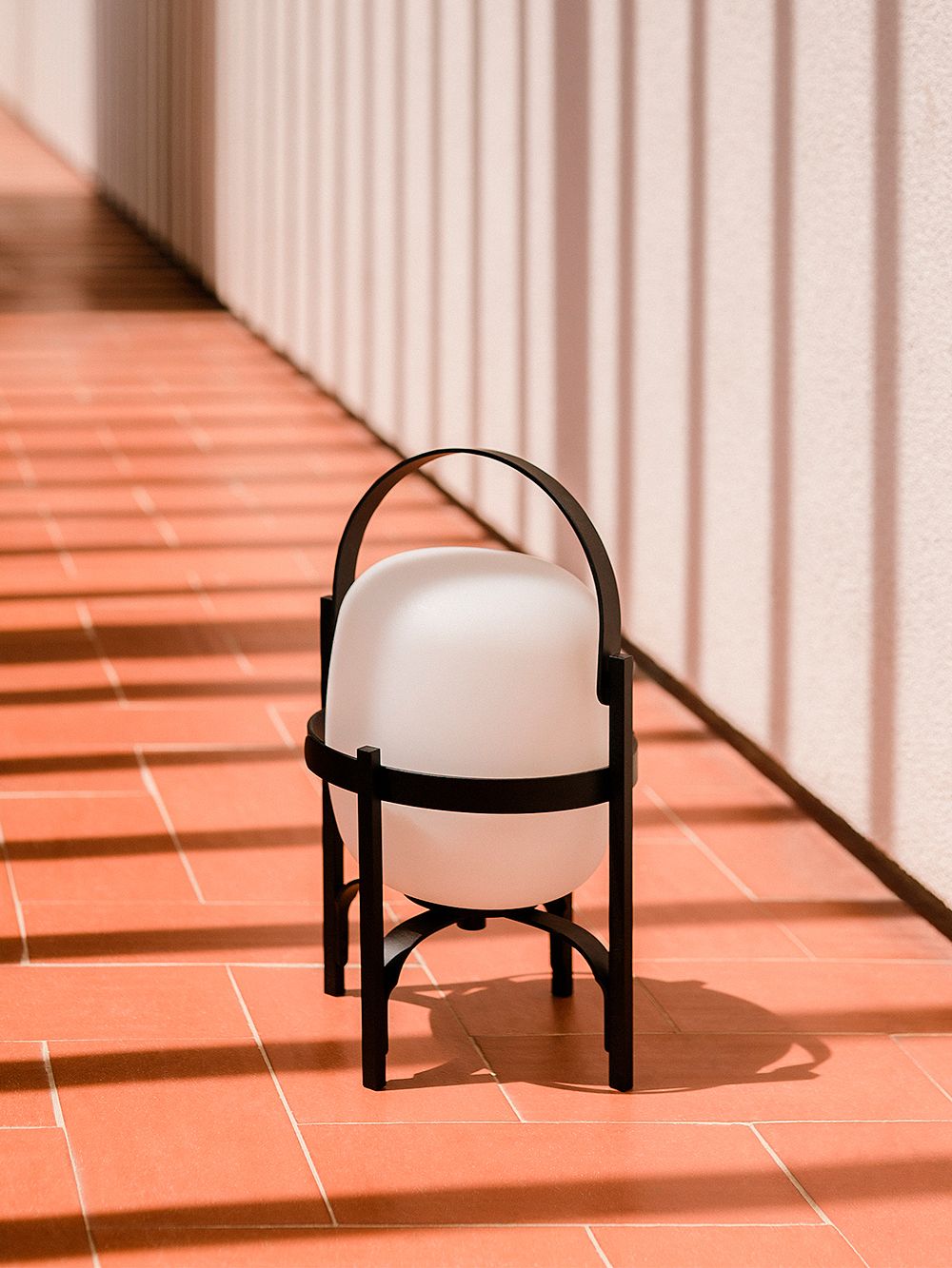 A product image of Santa & Cole's Cestita Alubat table lamp set on the floor.