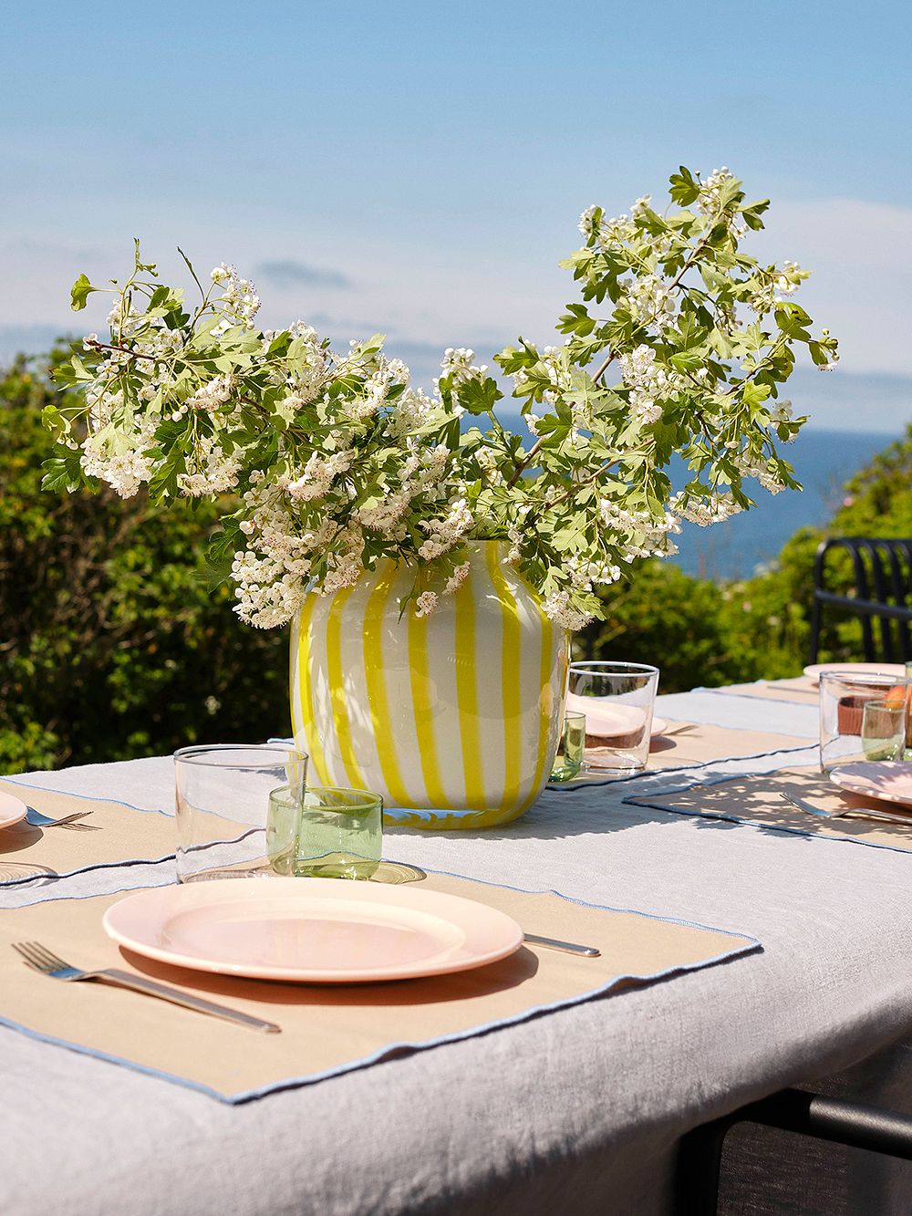 An image of HAY's yellow Juice vase in a table setting, as part of the summer house decor.